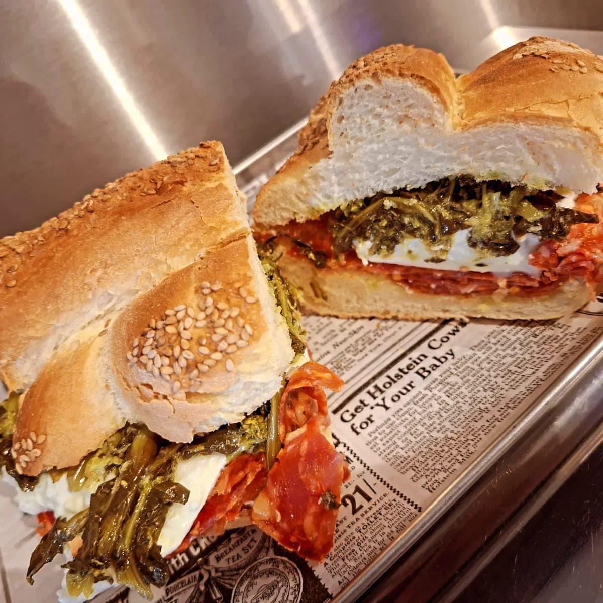 Une mafalda coupée en deux, garnie de charcuterie, de stracciatella et de légumes verts, posée sur le plateau du comptoir